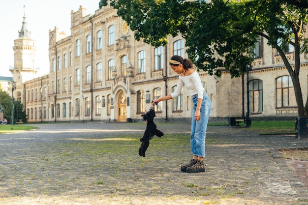 Dueño de perro positivo jugando con mascota en la calle con el telón de fondo de una hermosa vista