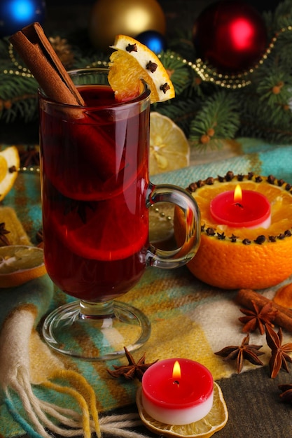 Duftender Glühwein im Glas mit Gewürzen und Orangen auf Holztisch