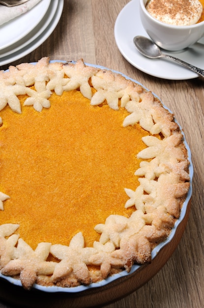 Duftender Herbstkürbiskuchen auf dem Tisch mit einer Tasse Kürbiskaffee mit Sahne und Zimt