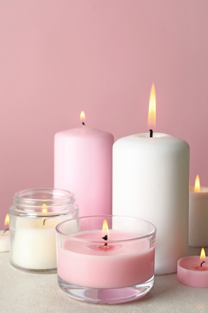 Duftkerzen zur Entspannung auf weißem Tisch gegen rosa Oberfläche