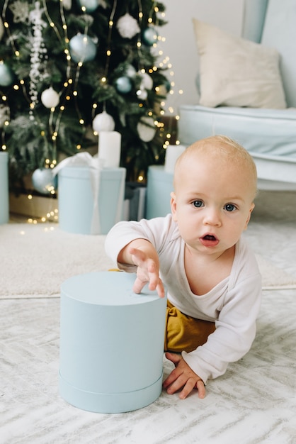 Dulce bebé caucásico jugando con un regalo de Navidad envuelto