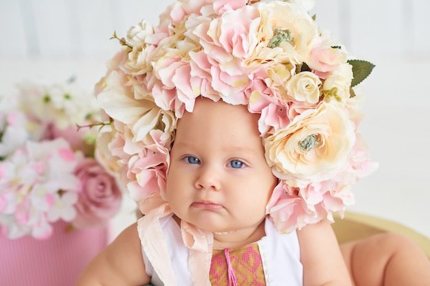 Dulce bebé gracioso en sombrero con flores. Pascua de Resurrección. Linda niña de 6 meses con sombrero de flores.