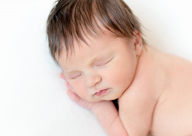 Dulce bebé recién nacido durmiendo en una manta blanca
