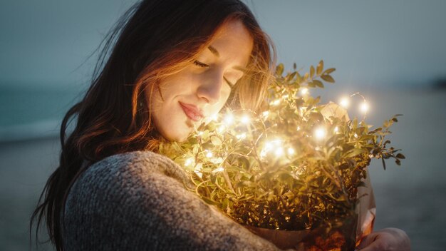 Foto la dulce chica se aprieta un ramo de flores con luces