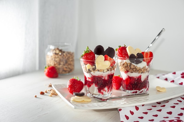 Dulce desayuno el día de san valentín en una mesa de madera blanca postre cremoso con fresas maduras y