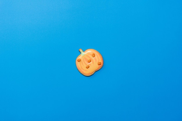 Dulce galleta de calabaza casera con glaseado aislado sobre fondo azul oscuro mínimo plano