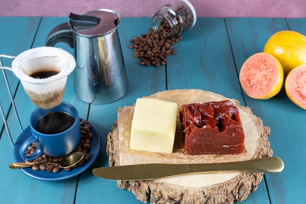 Dulce de guayaba con queso en una tabla de madera junto a una taza de cuchillo y granos de café