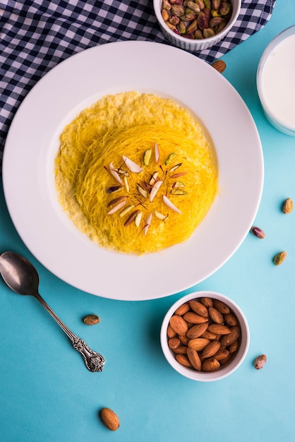 Dulce indio kesar sutarfeni o sutar feni o firni o seviyan o laccha, rallado, copos de harina de arroz tostado en ghee, mezclado con azúcar derretido para formar un algodón de azúcar, con pistacho y almendras