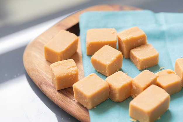 Dulce de leche en cubos sobre una tabla de madera con servilleta en la composición de la imagen