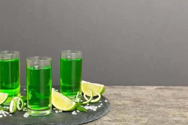 Dulce licor de menta refrescante con hielo y hojas de menta sobre el fondo de la mesa Chupitos con rodaja de lima y menta plana