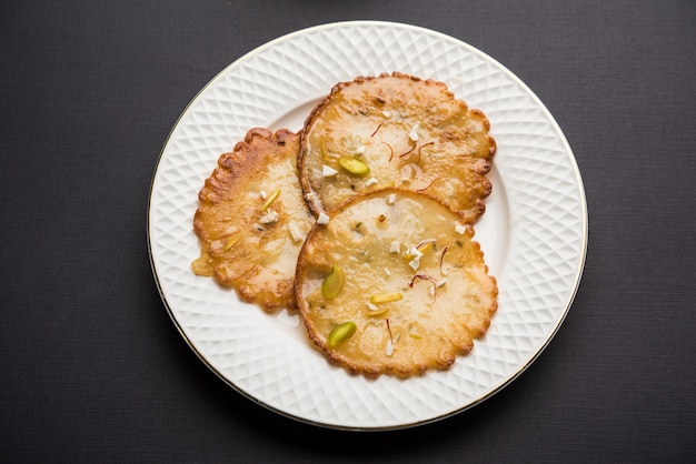 Dulce Malpua - Postre tradicional indio o panqueque para festivales, servido en plato con rabri o rabdi. enfoque selectivo