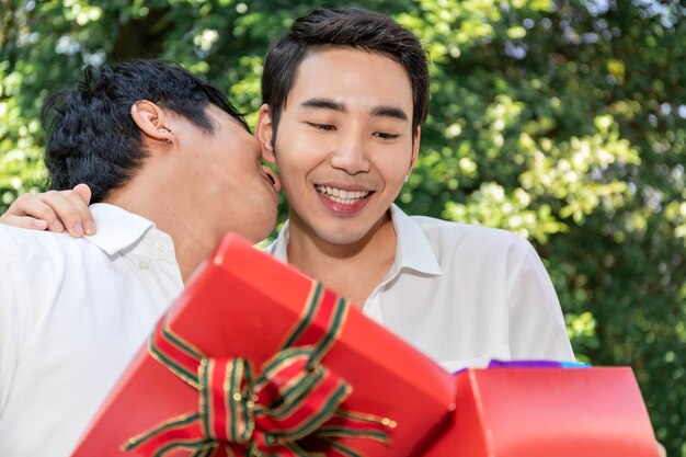 Dulce momento de amor Retrato de pareja de homosexuales asiáticos abrazo y caja de regalo sorpresa para novio