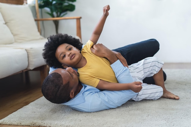 Foto dulce momento del concepto de paternidad feliz padre afroamericano abrazando y haciéndole cosquillas a su hijo