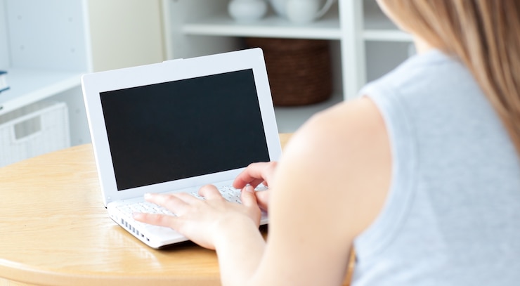 Foto dulce mujer sentada frente a su computadora portátil