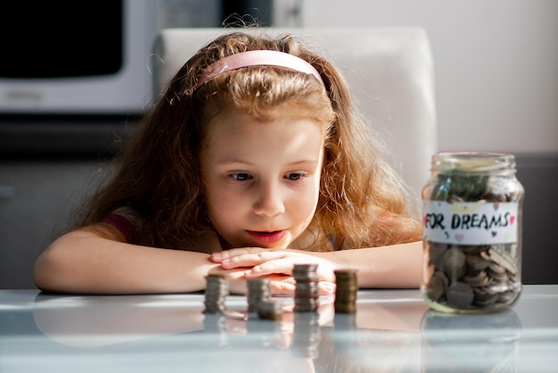 Una dulce niña con una alcancía llena de monedas El dinero Ahorro Infancia