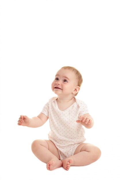 Foto dulce niña sentada aislada sobre fondo blanco.