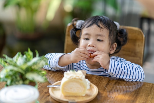 Dulce niña del sudeste asiático comiendo un trozo de pastel