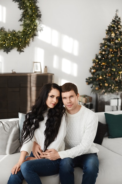 Dulce pareja de enamorados, guapo y su hermosa novia en el interior de Navidad