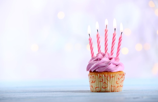 Dulce pastel sabroso con velas en la mesa de madera azul contra un fondo borroso