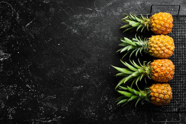 Foto dulce piña bebé sobre un fondo de piedra negra frutas tropicales vista superior espacio libre para texto