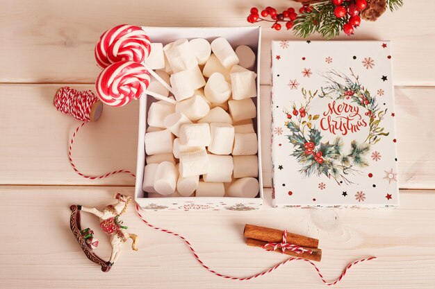 Dulces de año nuevo malvaviscos, piruletas y leche en la mesa con regalos