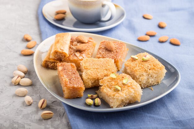 Dulces árabes tradicionales y una taza de café sobre un fondo de hormigón gris. Vista lateral, enfoque selectivo.