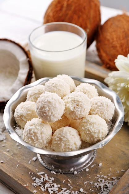 Dulces caseros en copos de coco y coco fresco en bandeja, primer plano