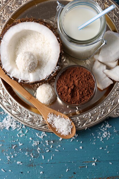Foto dulces caseros en copos de coco e ingredientes sobre fondo de madera de color