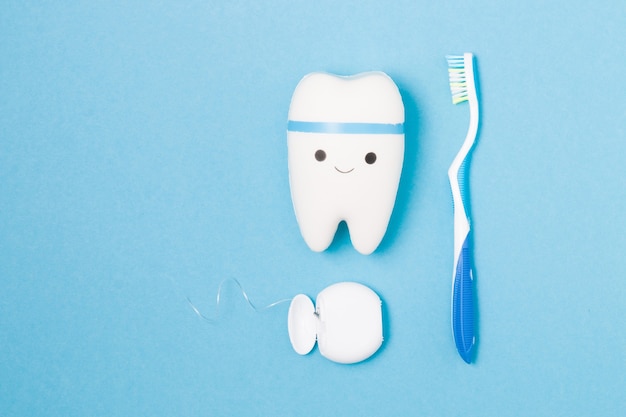 Dulces, cepillo de dientes, hilo dental y diente de juguete sobre una superficie azul