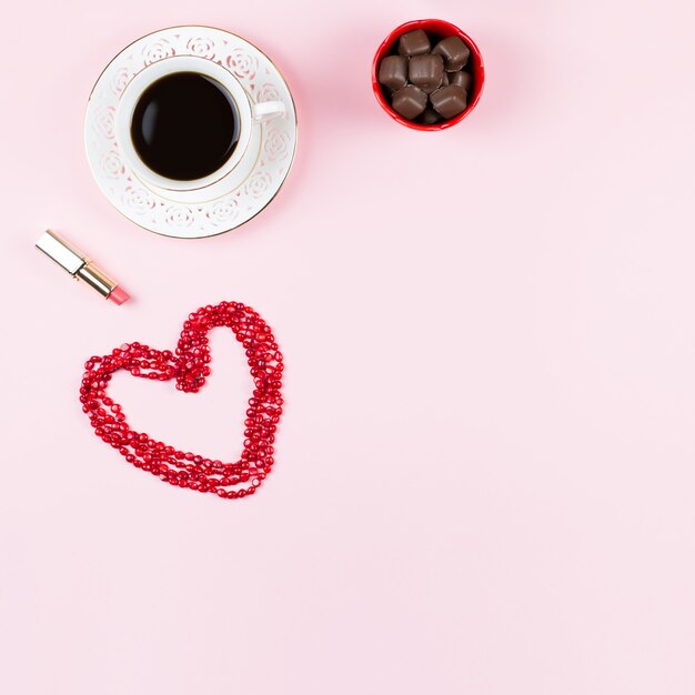 Dulces de chocolate, café negro, lápiz labial. Fondo femenino en colores rojo y blanco.