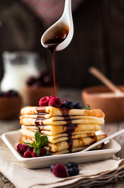 Dulces crepes de panqueques caseros de estilo francés y ruso. Pastel de crepe en capas con crema batida y bayas frescas