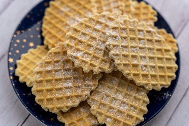 Dulces y deliciosos gofres crujientes espolvoreados con azúcar en polvo en un plato