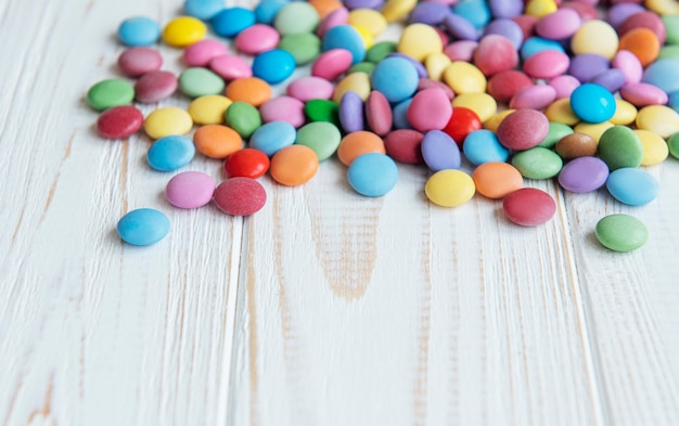 Dulces de grageas multicolores sobre una superficie de madera blanca