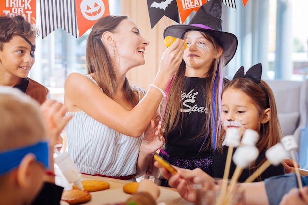 Dulces de Halloween. Madre morena divirtiéndose con los niños mientras hace dulces de Halloween para la fiesta familiar