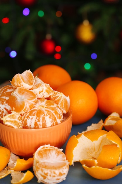 Dulces mandarinas y naranjas en la mesa sobre fondo de árbol de Navidad