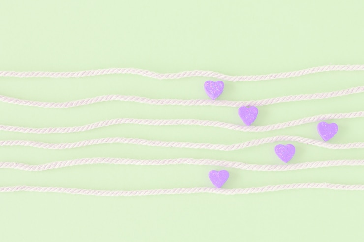 Foto dulces mini corazones en colorido sobre cuerda blanca en fondo pastel