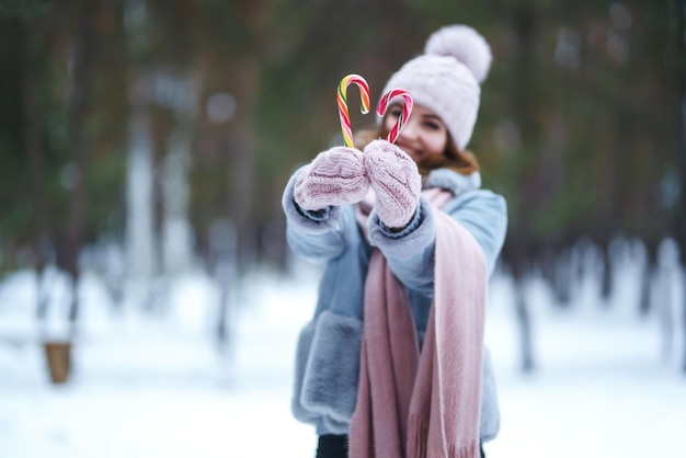 Dulces de Navidad en manos de una hermosa niña en el bosque Bastones de caramelo de rayas de Navidad Dulces.