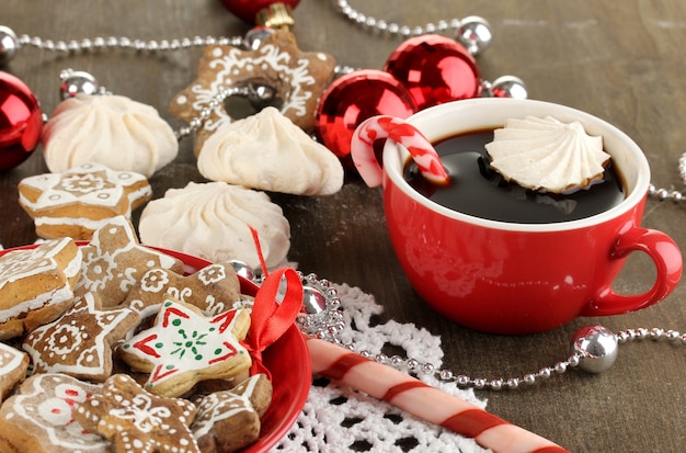 Dulces navideños en plato y taza de café en primer plano de la mesa de madera