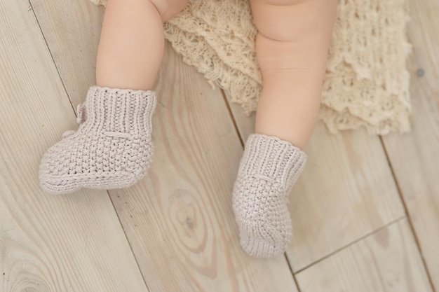 Foto dulces niños sin cara en cómodos calcetines de punto beige en el suelo de madera