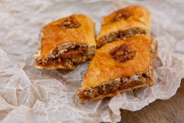 Dulces orientales - postre baklava, decorado con nuez en la parte superior, sobre papel de horno