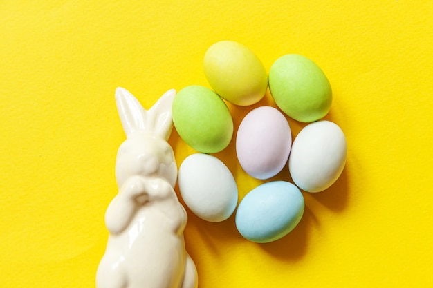 Dulces de Pascua huevos de chocolate dulces y juguete de conejito aislado sobre fondo amarillo de moda