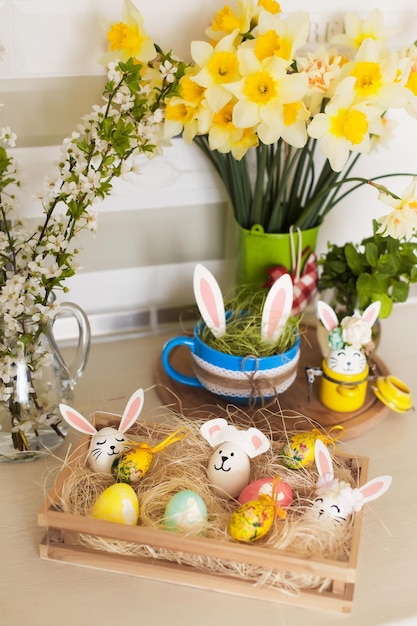 Dulces de Pascua y huevos decorativos con divertidas orejas de conejo en la mesa de la cocina