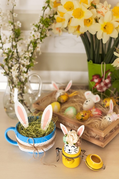 Dulces de Pascua y huevos decorativos con divertidas orejas de conejo en la mesa de la cocina