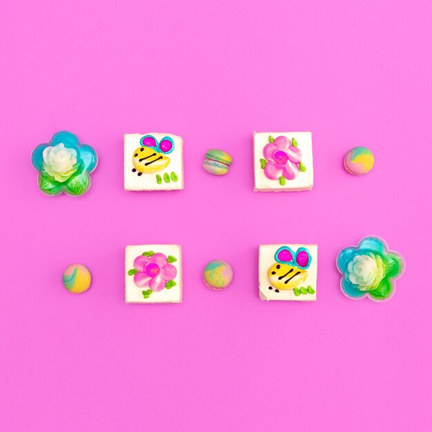 Dulces de pastel lindo en fondo rosa. Arte minimalista con estilo de comida plana