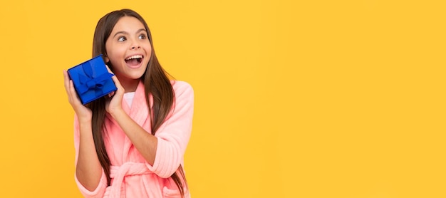 Dulces sueños pijama cómodo o albornoz casero niña adolescente sintiéndose sorprendida Niño niña con cartel horizontal de regalo Encabezado de pancarta con espacio de copia