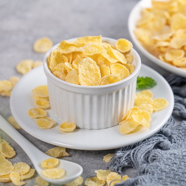 Dulces de tazón de copos de maíz con leche sobre fondo de cemento gris, concepto de diseño de desayuno fresco y saludable de cerca.