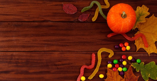 Dulces tradicionales de Halloween Calabazas hojas de otoño y dulces sobre fondo de madera