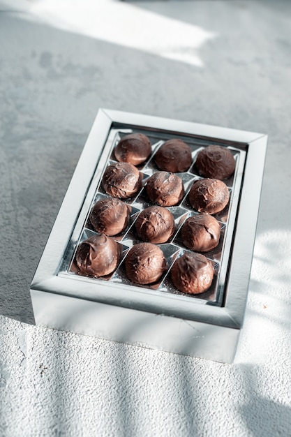 Dulces de trufa de chocolate surtidos artesanales en caja sobre fondo de piedra blanca