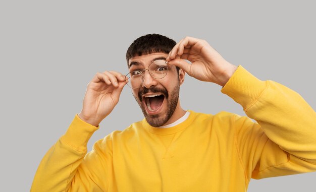 dummer junger Mann mit Brille und gelbem Sweatshirt