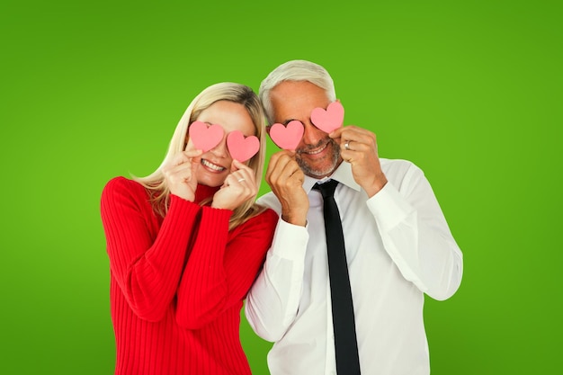 Foto dummes paar, das herzen über ihren augen gegen grüne vignette hält